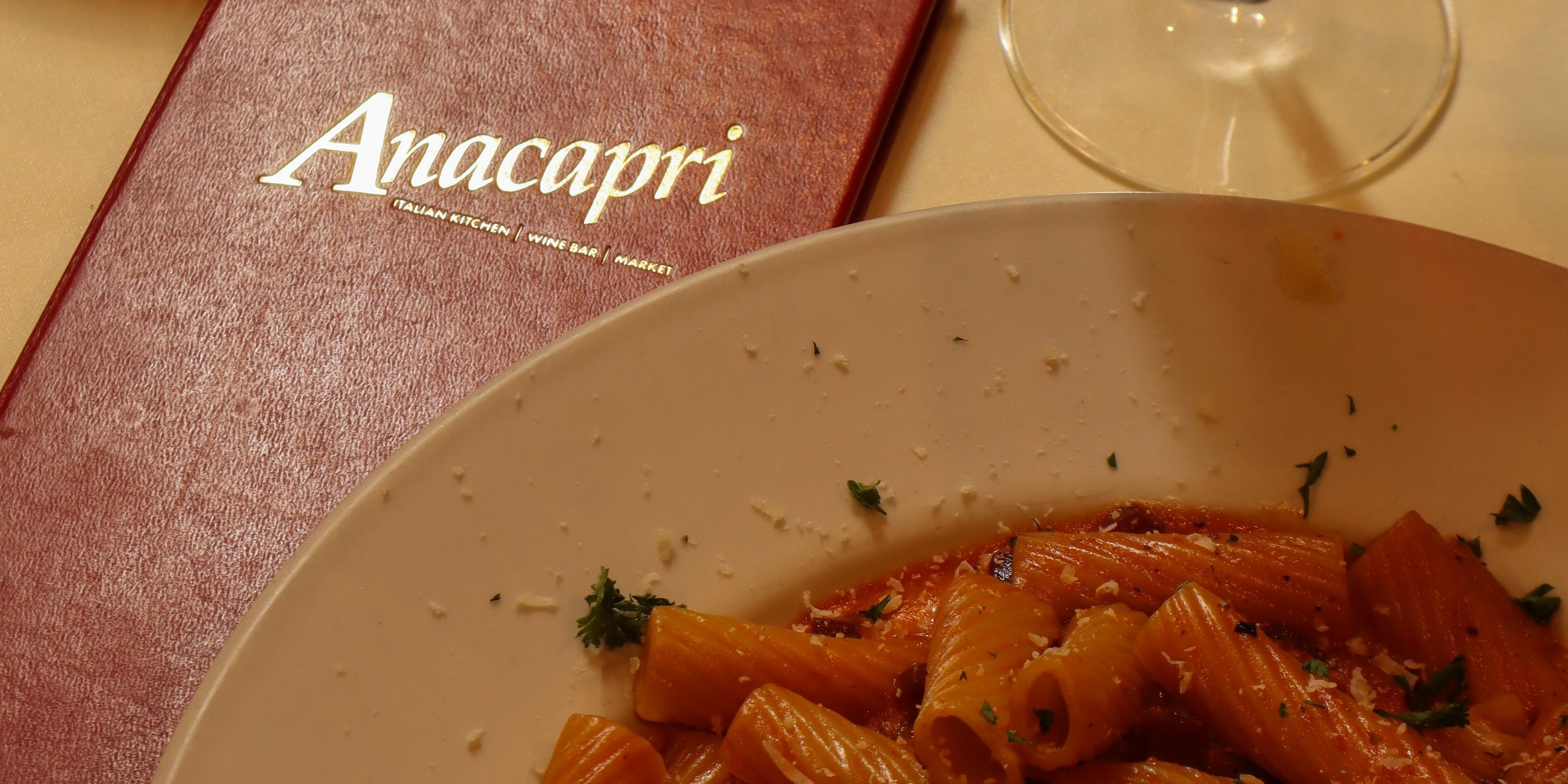 a plate of pink rigatoni pasta and the Anacapri Menu in Red on a tablescape